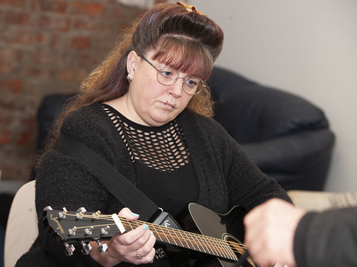 Adult playing guitar in workshop