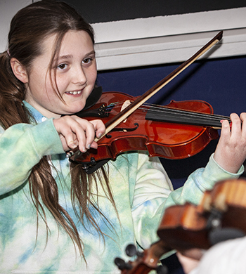young person with fiddle in workshop